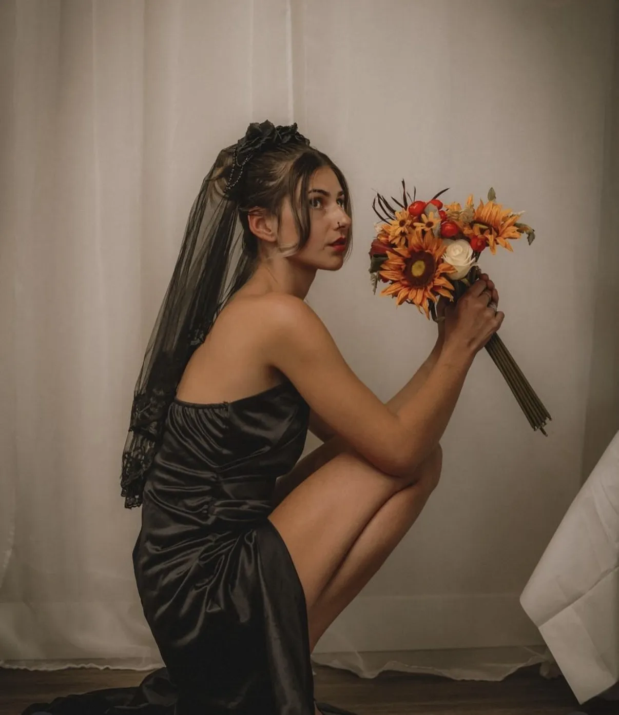 Bride with an autumn sunflower bouquet against draped curtains